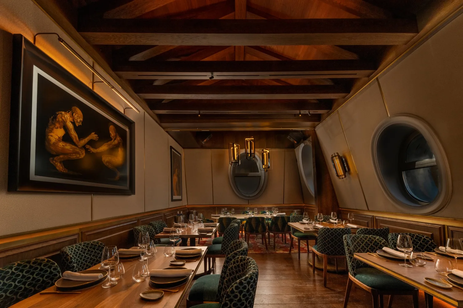 Salón bajo cubierta con vigas de madera y ventanas ovaladas