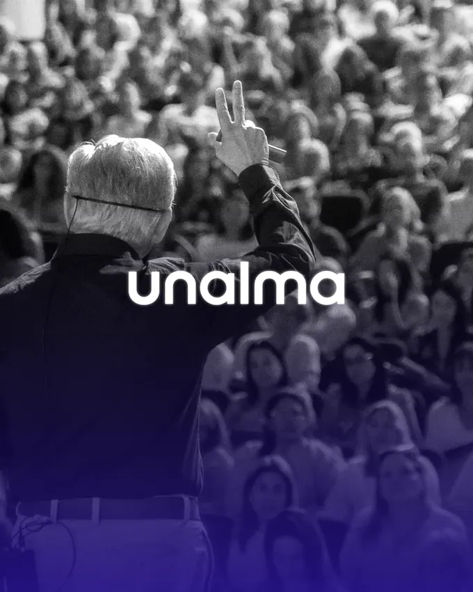 Logotipo de Unalma sobre la foto de un conferencista frente a un auditorio lleno, con degradado violeta